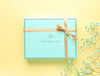 Blue gift box with a golden ribbon, decorated with blue flowers