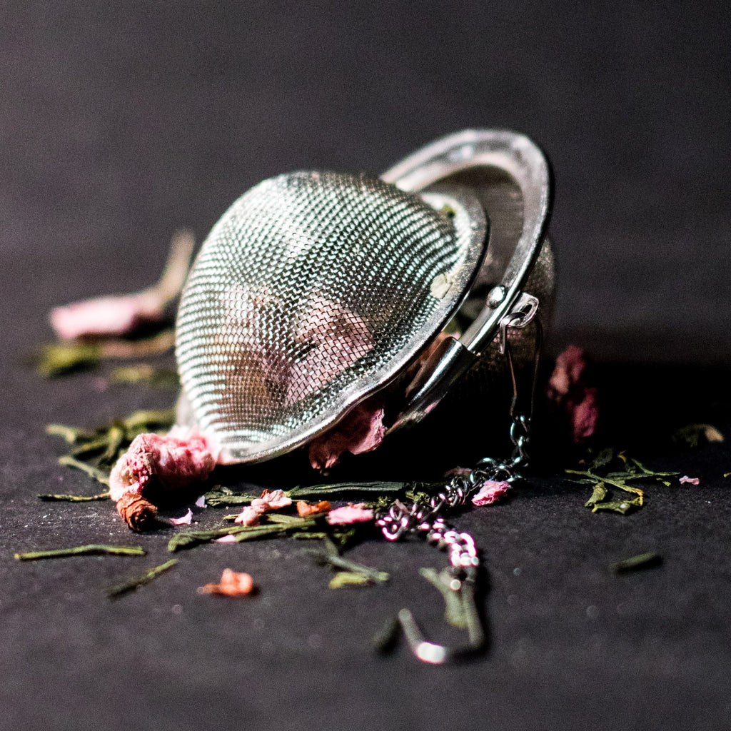 Loose leaf tea emerging from a strainer on a grey surface