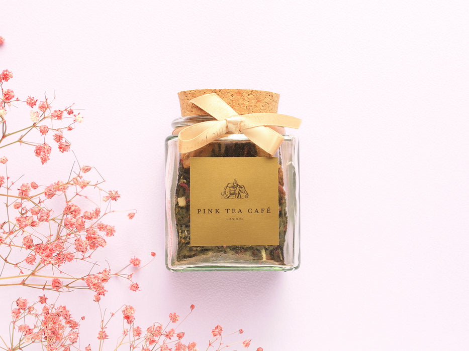 Square glass jar with golden ribbon and golden ribbon, decorated with pink flowers