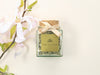 Square glass jar with a golden ribbon filled with Japan Matcha Genmaicha 