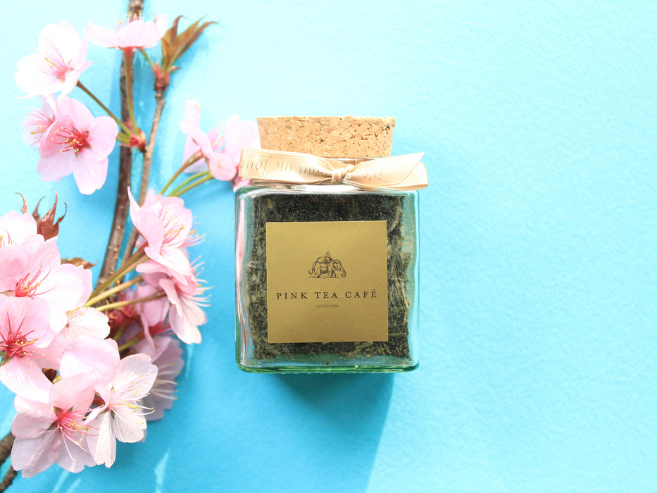 Square glass jar with golden ribbon and cork lid, decorated with pink flowers