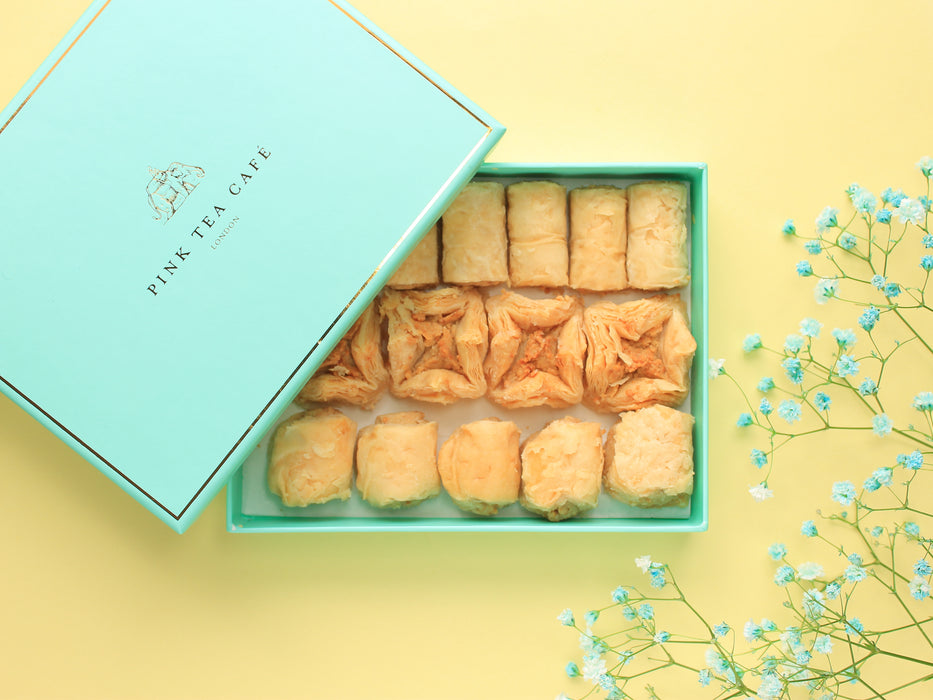 Half open, blue gift box filled with delicious light baklava, decorated with blue little flowers